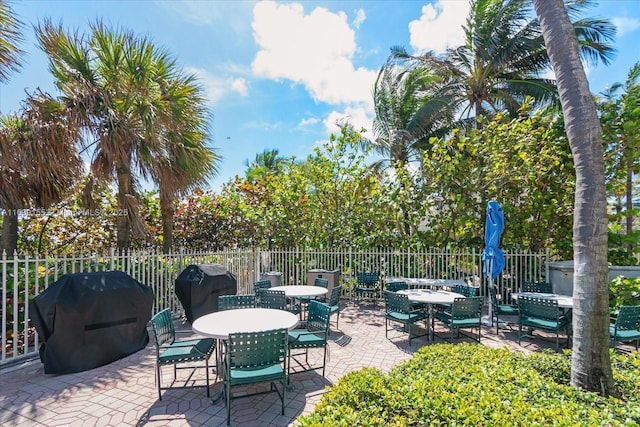 view of patio with grilling area, outdoor dining area, and fence