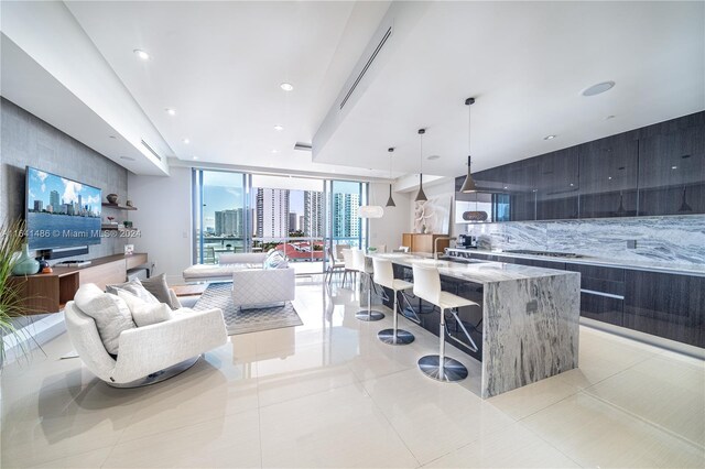 kitchen with decorative light fixtures, a large island, modern cabinets, decorative backsplash, and light stone countertops