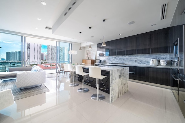 kitchen featuring decorative backsplash, modern cabinets, decorative light fixtures, a city view, and a large island with sink