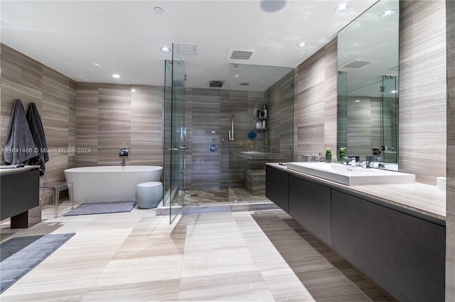 full bathroom featuring a soaking tub, vanity, tile walls, and a shower stall