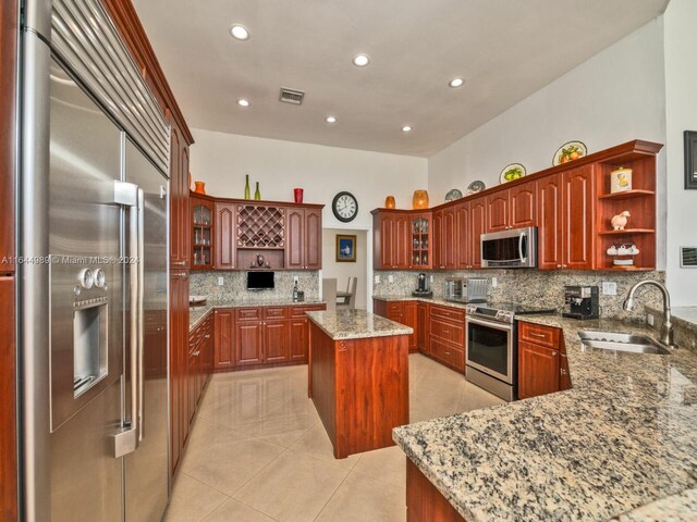 175 SW 132nd Ave, Miami, FL 33184 - kitchen featuring appliances with stainless steel finishes, a sink, open shelves, light stone countertops, and a kitchen island