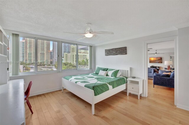 bedroom with a textured ceiling, light hardwood / wood-style flooring, and ceiling fan