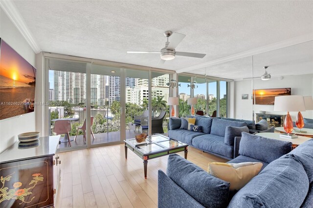 living room featuring a wall of windows, ceiling fan, a textured ceiling, and light wood-type flooring