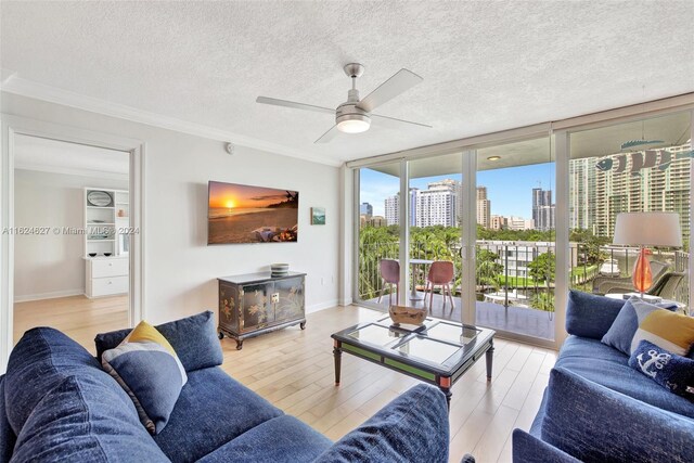 living room featuring ornamental molding, light wood-type flooring, expansive windows, a textured ceiling, and ceiling fan