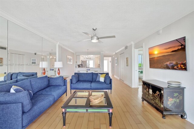 living room with a textured ceiling, light hardwood / wood-style flooring, crown molding, and ceiling fan with notable chandelier