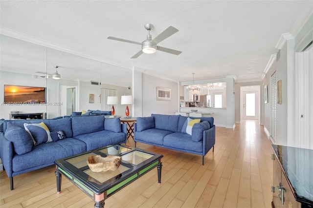 living room featuring ceiling fan with notable chandelier, a textured ceiling, light hardwood / wood-style floors, and ornamental molding