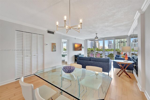 dining area with ceiling fan with notable chandelier, light hardwood / wood-style flooring, ornamental molding, and a textured ceiling