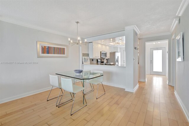 dining area with a textured ceiling, light hardwood / wood-style floors, a chandelier, and ornamental molding