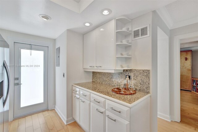 kitchen featuring white cabinetry, light hardwood / wood-style floors, electric panel, and backsplash