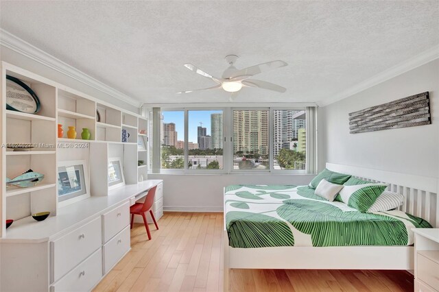 bedroom featuring ceiling fan, light wood-type flooring, a textured ceiling, and ornamental molding