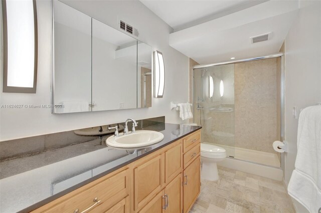 bathroom with a shower with shower door, toilet, tile patterned flooring, and vanity