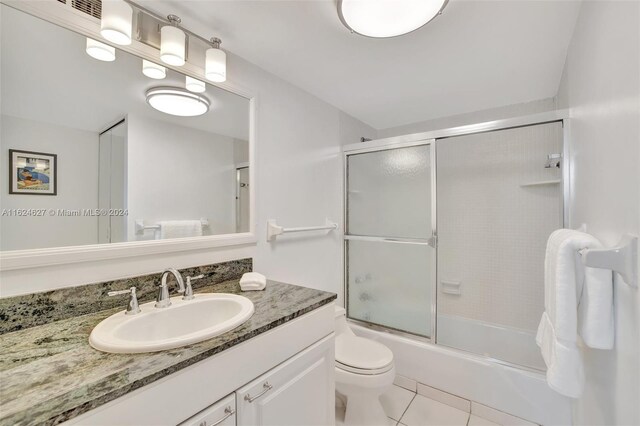 full bathroom featuring tile patterned floors, vanity, shower / bath combination with glass door, and toilet