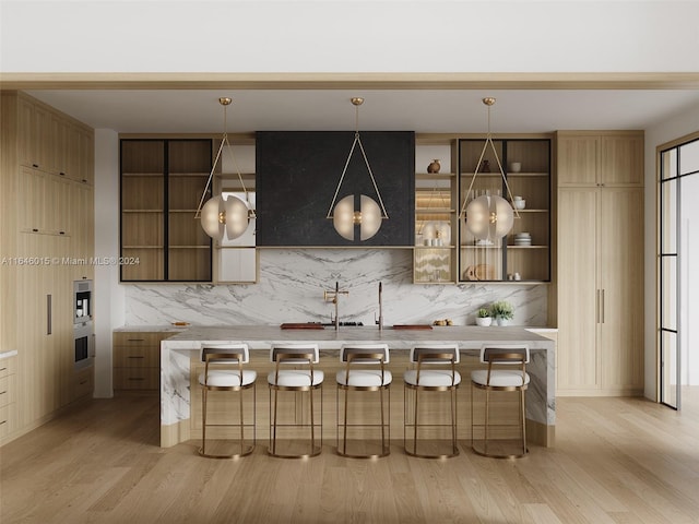 bar featuring stainless steel oven, pendant lighting, light wood-type flooring, and tasteful backsplash