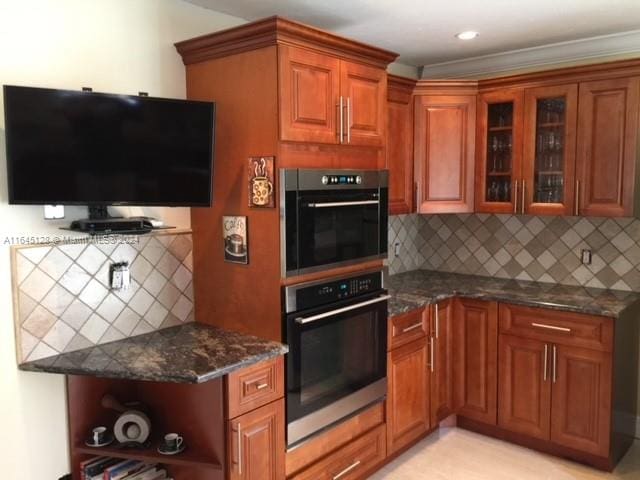 kitchen featuring double oven, dark stone countertops, and decorative backsplash