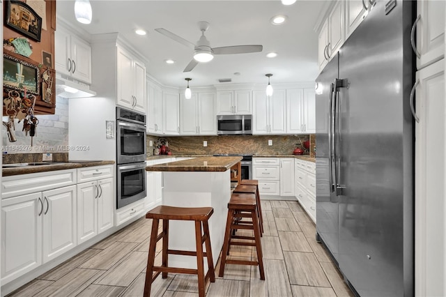 kitchen featuring white cabinets, hanging light fixtures, a center island, appliances with stainless steel finishes, and ceiling fan