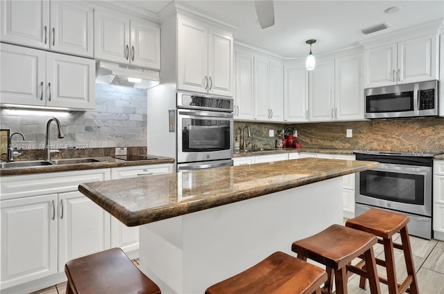 kitchen featuring decorative light fixtures, stainless steel appliances, sink, a breakfast bar area, and decorative backsplash