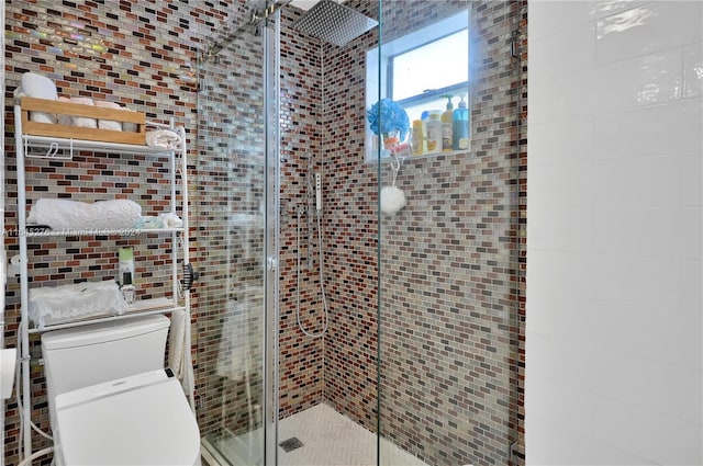 bathroom with tile walls, toilet, and a shower with shower door