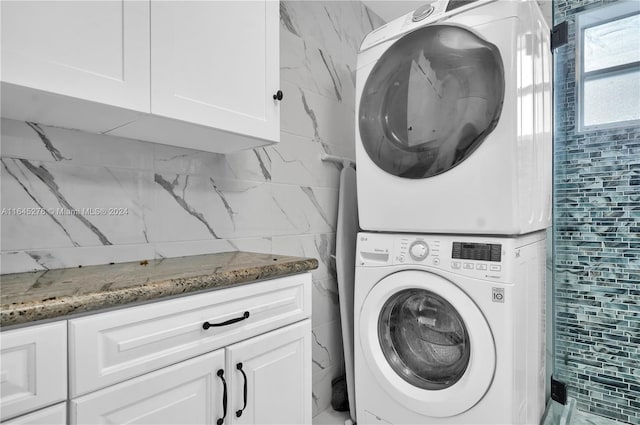 laundry area featuring cabinets and stacked washer and dryer