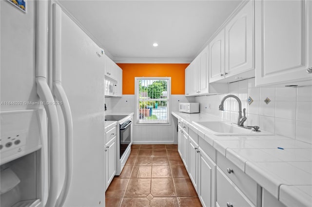 kitchen featuring sink, white appliances, white cabinetry, tasteful backsplash, and tile counters