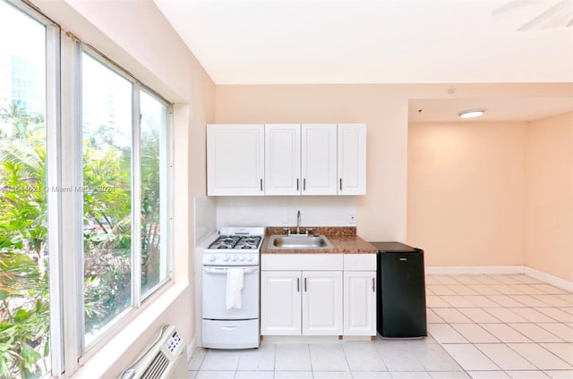 kitchen featuring light tile patterned floors, white range with gas stovetop, sink, and white cabinetry