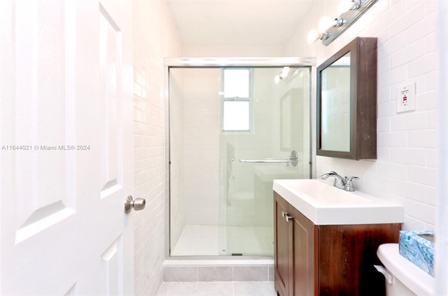 bathroom with toilet, tile walls, vanity, and a shower with shower door