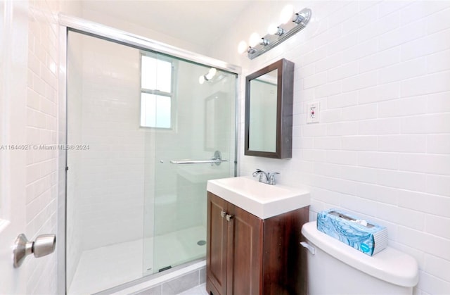 bathroom featuring tile walls, an enclosed shower, vanity, and toilet