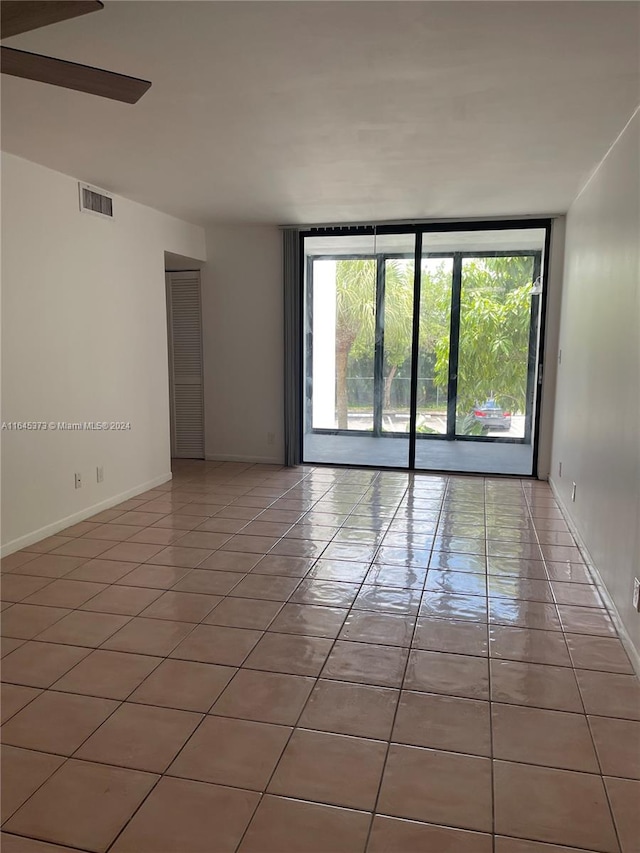 empty room with ceiling fan, tile patterned flooring, and floor to ceiling windows