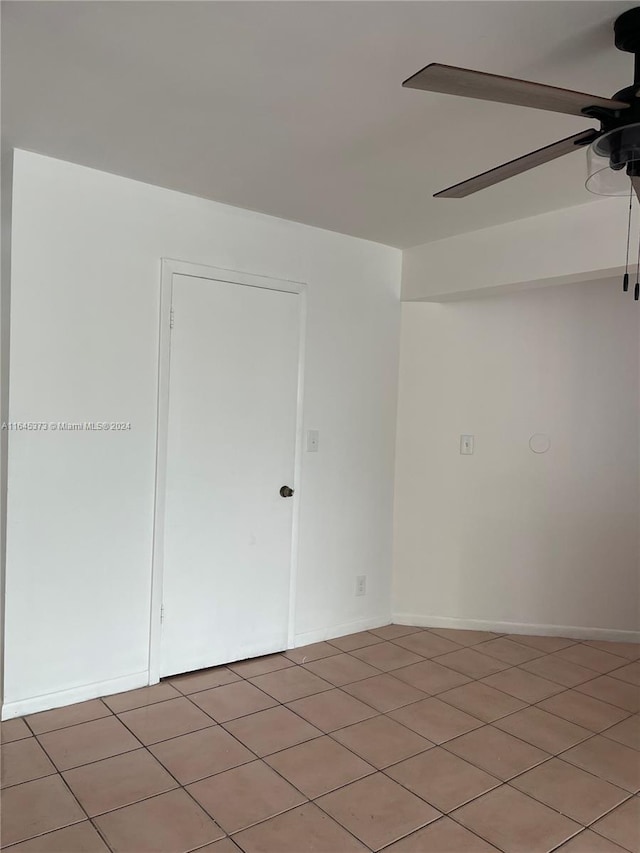 empty room with ceiling fan and tile patterned flooring