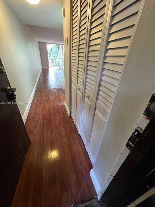 corridor with baseboards and dark wood finished floors