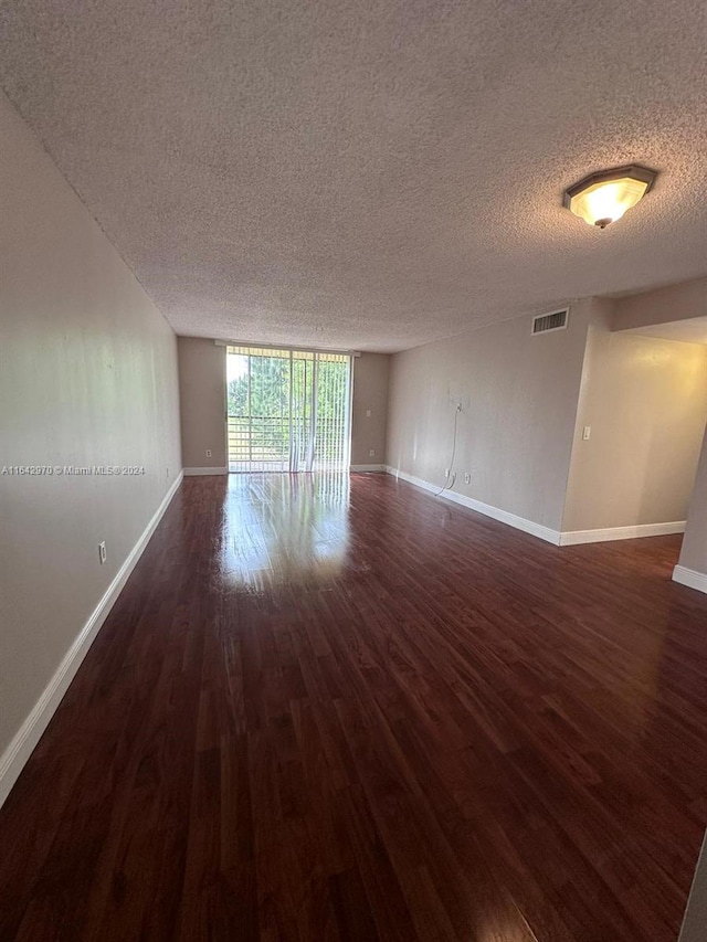 spare room featuring hardwood / wood-style floors, a wall of windows, and a textured ceiling