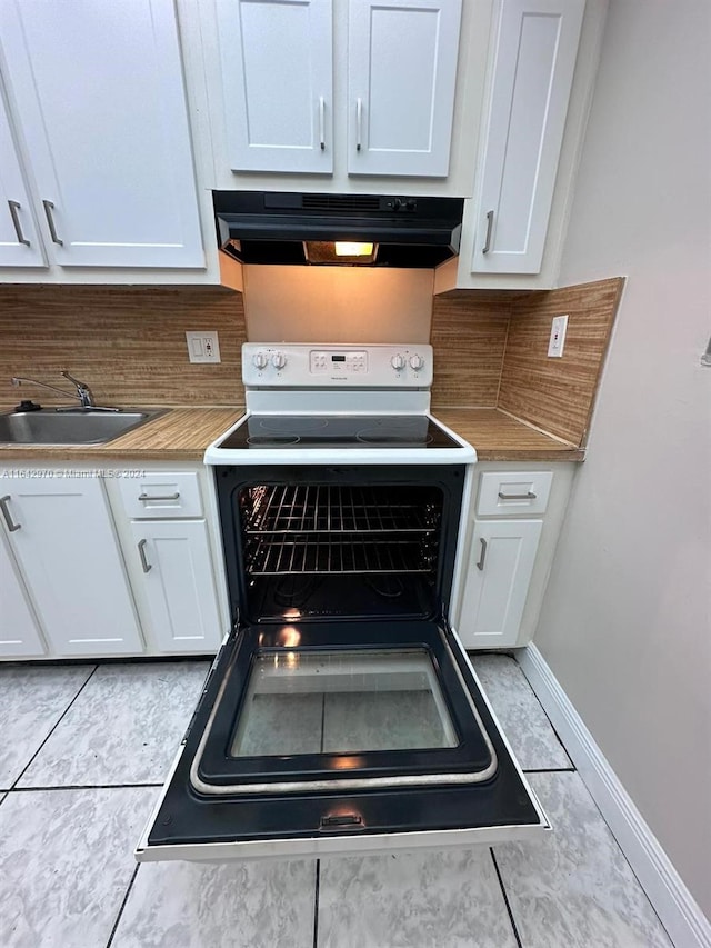 details featuring white cabinets, a sink, electric range, light countertops, and under cabinet range hood