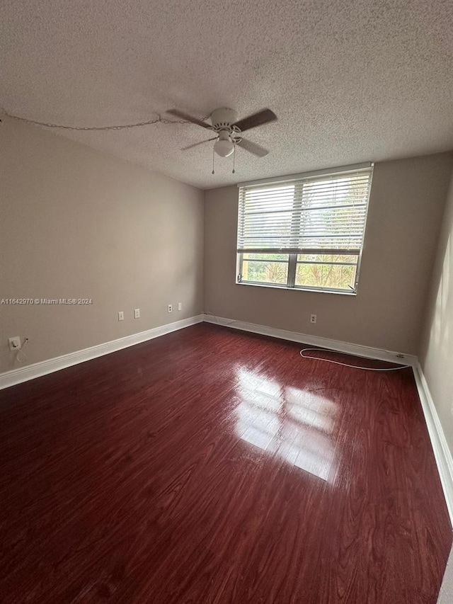 unfurnished room featuring ceiling fan, baseboards, dark wood-type flooring, and a textured ceiling