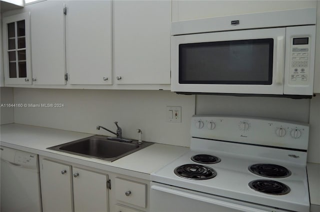 kitchen featuring white cabinetry, sink, and white appliances