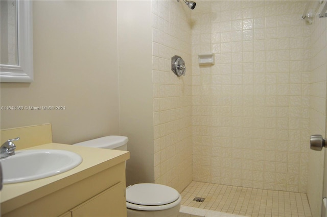 bathroom featuring toilet, a tile shower, and vanity