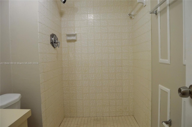 bathroom with toilet, tiled shower, and vanity