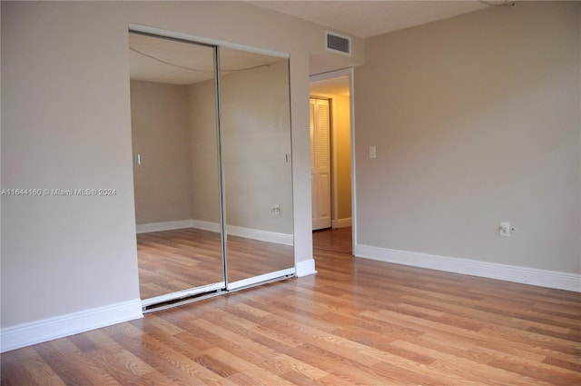 unfurnished bedroom featuring light hardwood / wood-style flooring and a closet