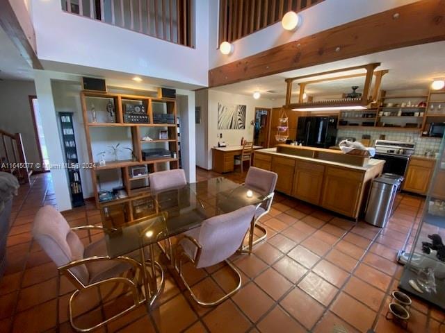 kitchen featuring backsplash, a high ceiling, tile countertops, light tile patterned floors, and refrigerator