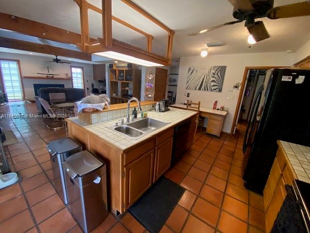 kitchen featuring ceiling fan, sink, tile counters, and light tile patterned floors