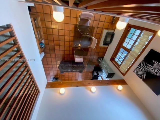 living room featuring tile walls, high vaulted ceiling, and beamed ceiling