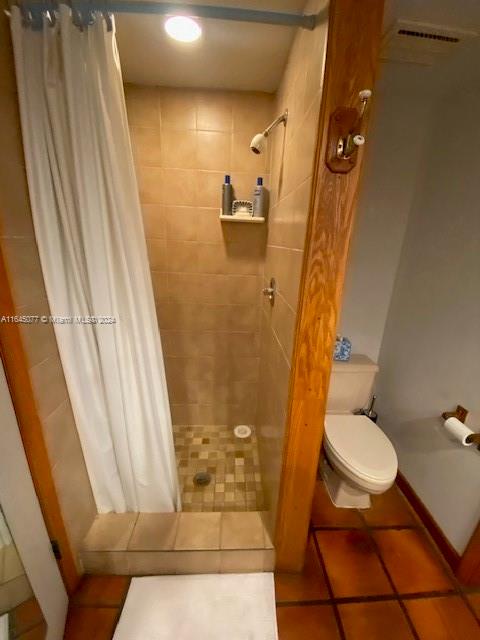 bathroom with toilet, tile patterned floors, and a shower with curtain