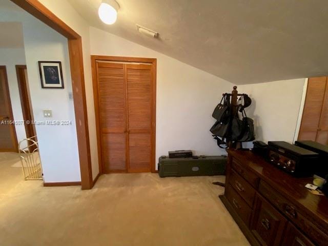 carpeted bedroom with a closet and lofted ceiling