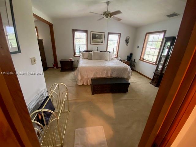 carpeted bedroom featuring ceiling fan and vaulted ceiling