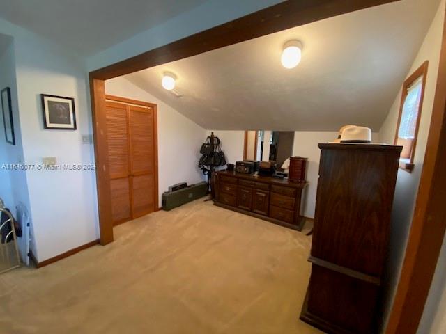 carpeted bedroom featuring vaulted ceiling with beams and a closet