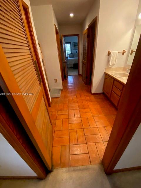 corridor with light tile patterned floors and sink