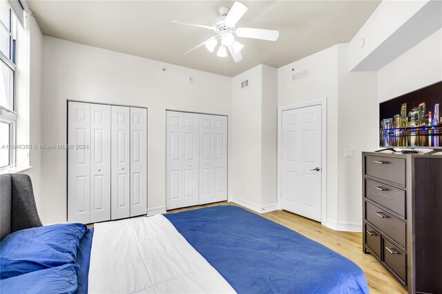 bedroom featuring ceiling fan, multiple closets, and light hardwood / wood-style floors