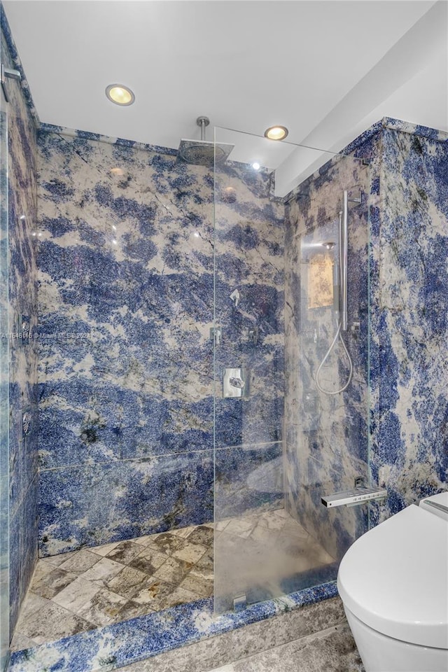 bathroom with toilet and a marble finish shower