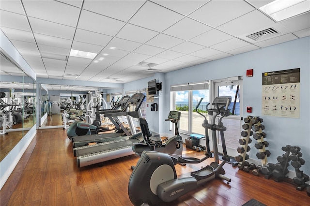 exercise room featuring a paneled ceiling, visible vents, and wood finished floors