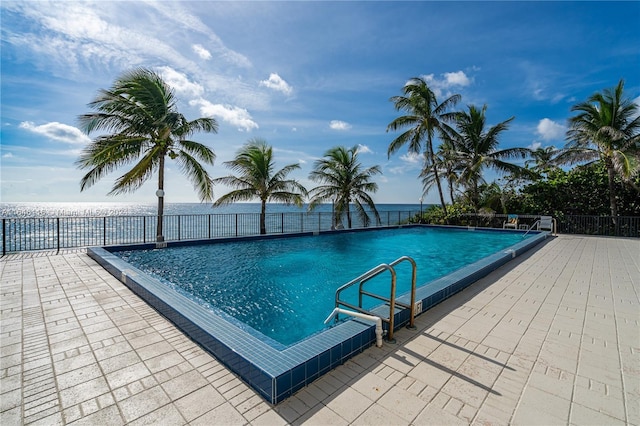 community pool with a patio area and fence