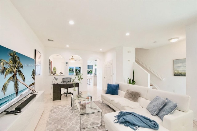 living room with arched walkways, light tile patterned flooring, recessed lighting, visible vents, and stairs