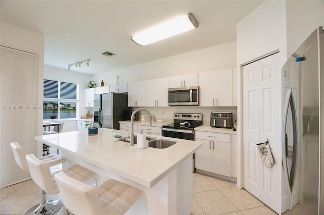 kitchen featuring an island with sink, appliances with stainless steel finishes, white cabinets, and a sink